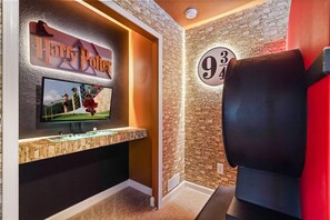A room with a stone wall, a Harry Potter sign, a television, and a fireplace.
