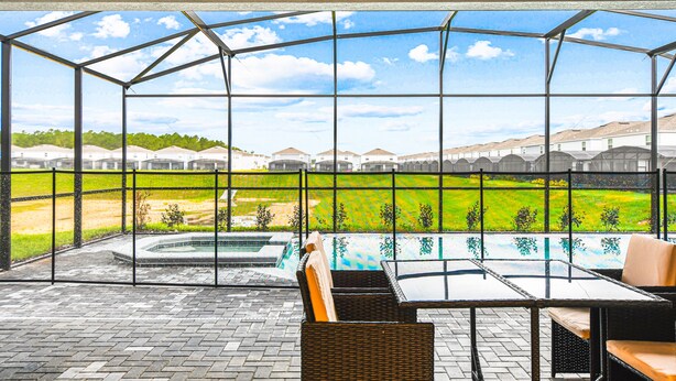 Un espace extérieur abrité avec une piscine, des sièges et une vue sur les maisons au loin.