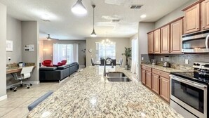 A spacious kitchen with granite countertops, wooden cabinets, and modern appliances.