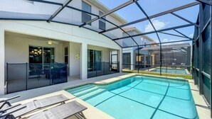 A modern outdoor pool area with glass enclosures, lounge chairs, and a clear view of the surrounding buildings.