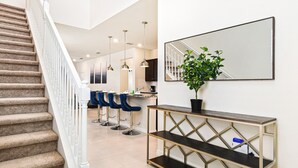 A modern kitchen with a central island, bar stools, pendant lighting, and a potted plant on a console table. - Last Minute Disney! Private Pool, Hot Tub & Themed Bedrooms. Book Now! #106587 (Orlando)