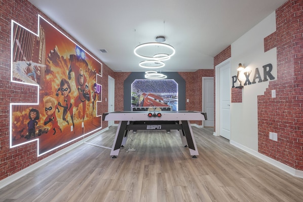 Relax in a vibrant room with a pool table and animated character murals, surrounded by a modern design.