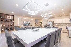 Enjoy meals in this spacious dining area with a large table and comfortable chairs, a mounted TV, and a fully equipped kitchen.