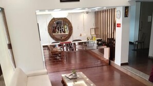 A spacious lobby with a white sofa, a wooden coffee table, and a large potted plant.