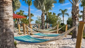 Ein Strandbereich mit Hängematten und Palmen.