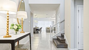 Ein geräumiger Flur mit Marmorboden, einer Treppe mit Holzstufen und einem Essbereich im Hintergrund.