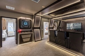 Un interior moderno con una zona de estar, una pantalla grande y un panel de control.