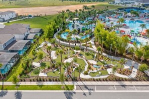 Een resort met een groot zwembad, palmbomen en een kronkelend waterlandschap.