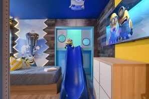 Een kamer met een bed, een blauwe glijbaan en Minion-decoraties.
