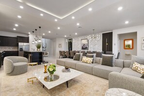 Een moderne woonkamer met een bank, salontafel en een eethoek met stoelen.