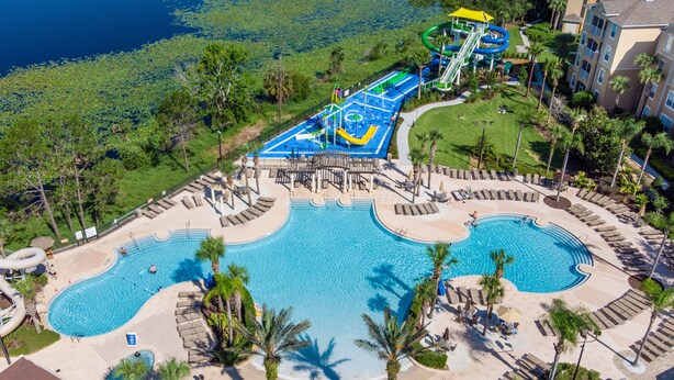 Oversigtsbillede af et resort med en stor swimmingpool, en vandpark og palmer.