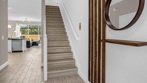 A staircase leading to a second floor, a kitchen area with a dining table, and a large mirror on the wall. - Last Minute Disney Getaway! Townhouse with Private Pool. Book Now! #66057 (Orlando)
