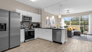 A modern kitchen with stainless steel appliances, a tiled backsplash, and a large island. - Last Minute Disney Getaway! Townhouse with Private Pool. Book Now! #66057 (Orlando)
