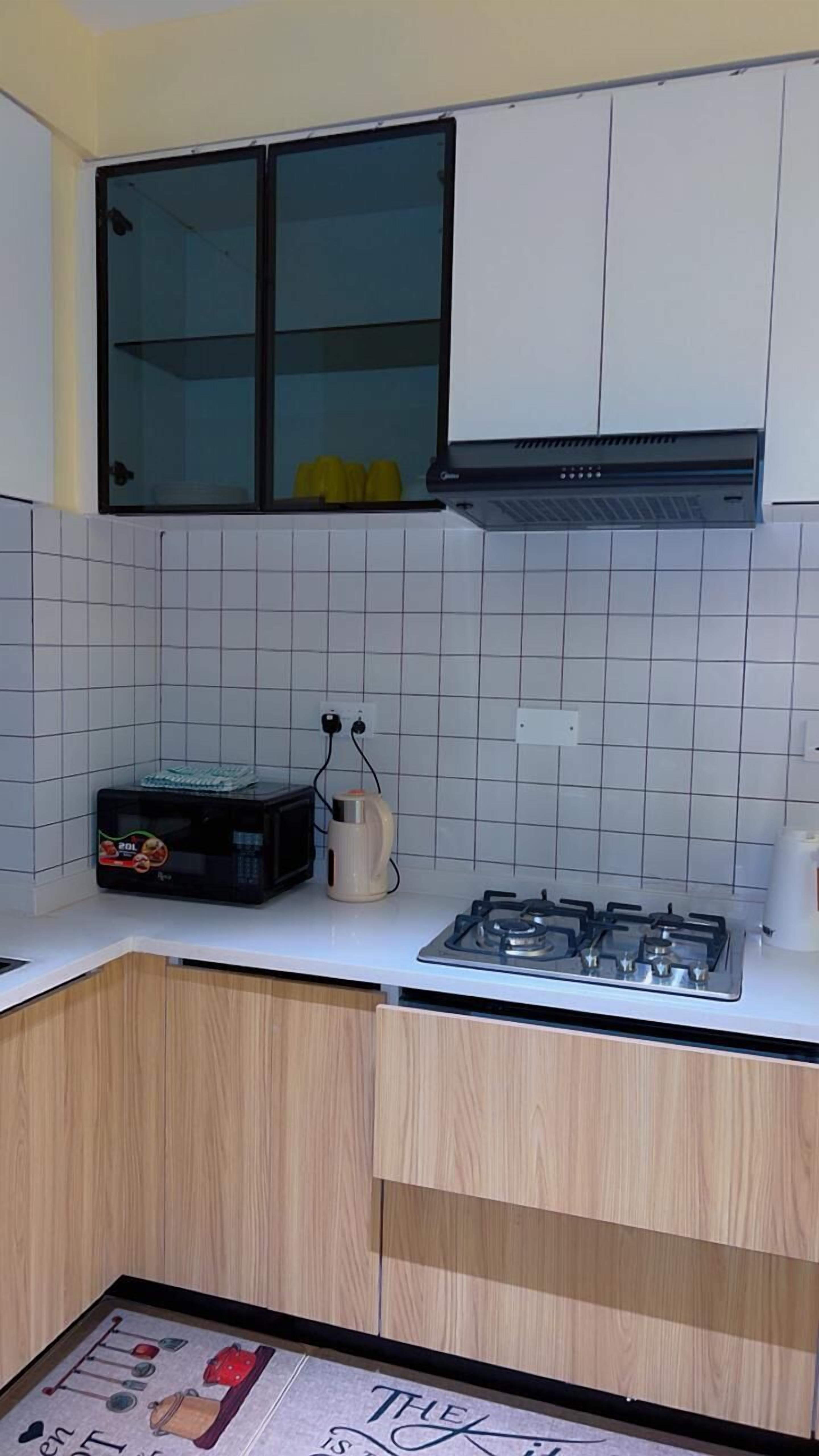 Een keuken met witte kastjes, een gasfornuis, een magnetron en een koffiezetapparaat.