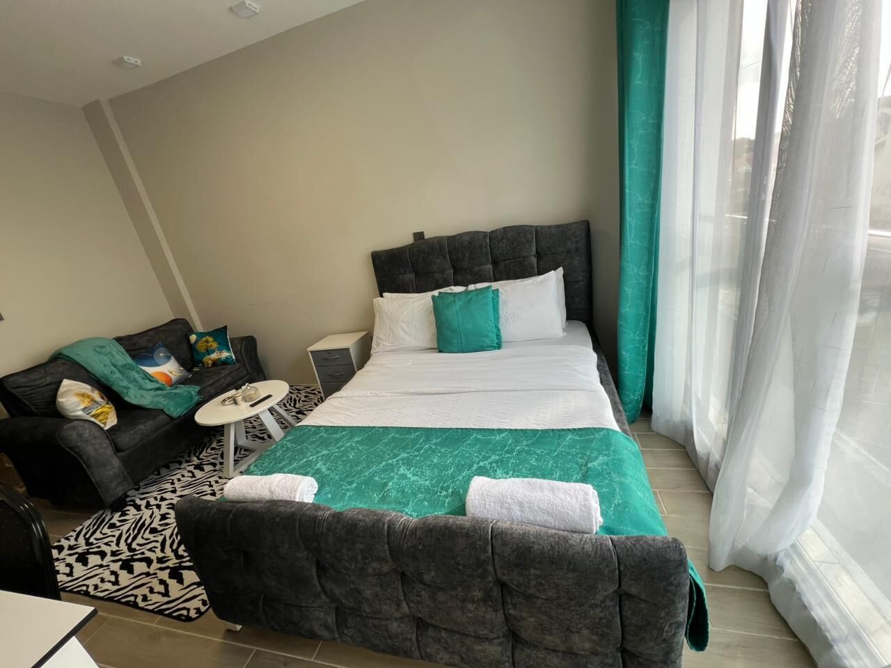 Ein Hotelzimmer mit einem großen Bett, einer Couch, einem kleinen Tisch und einem Fenster mit Vorhängen.