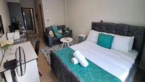 Une chambre d’hôtel avec un grand lit, un bureau avec un ordinateur, une chaise et une petite table.