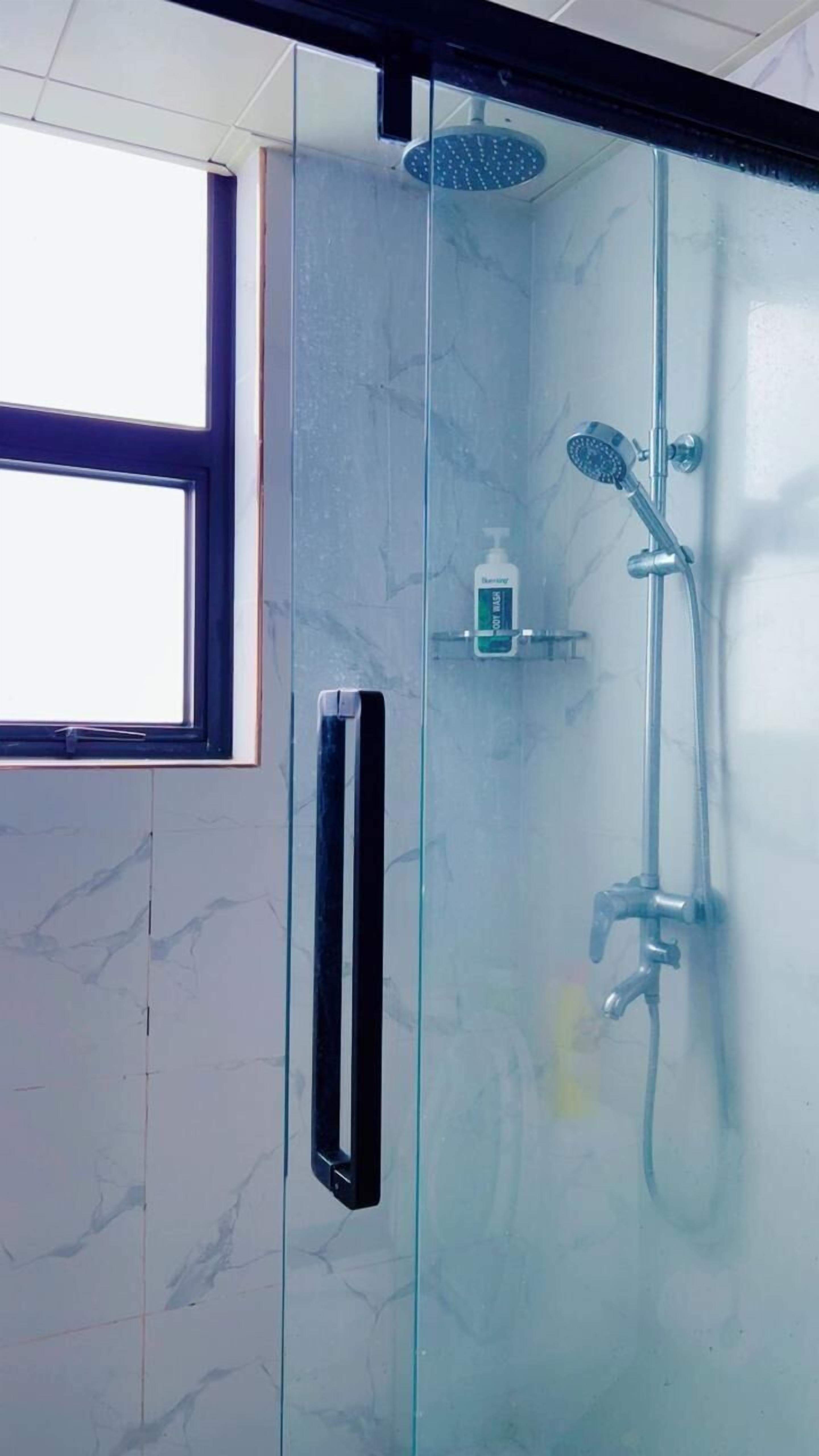 A glass-enclosed shower with a handheld showerhead and a wall-mounted faucet.