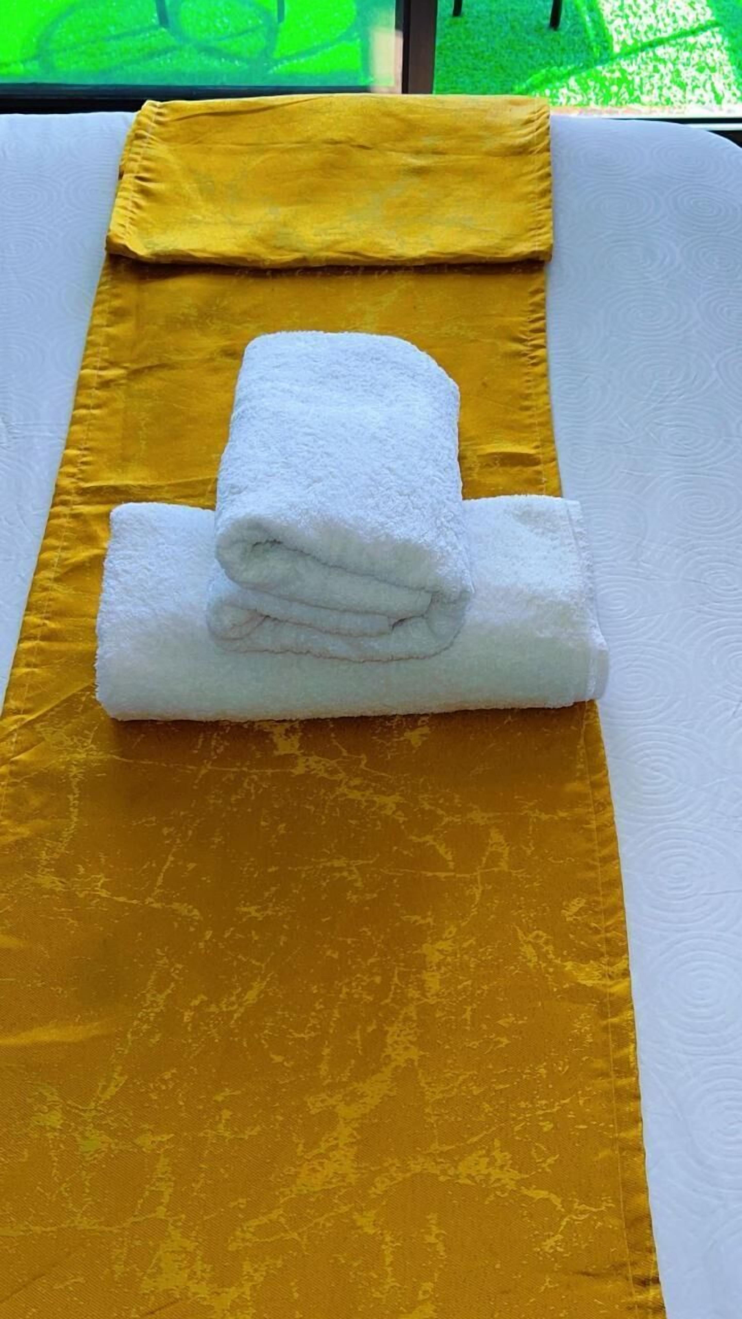Eine Massageliege mit einem gelben und einem gefalteten weißen Handtuch.