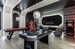 Quarto com mesa de bilhar, espaço de jogos e parede temática de Star Wars.