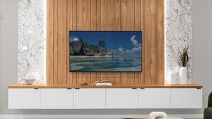 A modern living room with a large flat-screen TV mounted on a wooden panel wall.