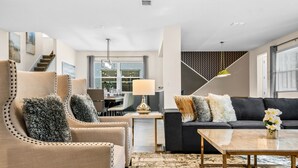 A modern living room with a sofa, armchairs, a coffee table, and a staircase. - Last Minute Disney! Private Pool, Hot Tub & Themed Bedrooms. Book Now! #91755 (Orlando)