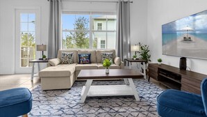 Ein Wohnzimmer mit Ecksofa, Couchtisch und Fernseher auf einem Holzgestell.