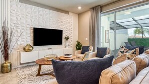 Una sala de estar moderna con un televisor de pantalla plana grande, asientos cómodos y vistas a través de un ventanal.