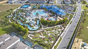 Ovenudblik over en resort med en central pool, flere vandrutsjebaner og forskellige udendørs siddeområder.
