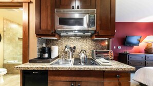 A compact kitchen with a built-in microwave, sink, and dishwasher. - Catamount Lodge 305A - Village Junior Studio (Truckee)