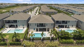 A residential complex with multiple two-story houses, each featuring a front yard with a swimming pool and a covered patio area. - Last Minute Disney! Private Pool, Hot Tub, Game Room & Themed Bedrooms. Book Now! #96895 (Orlando)
