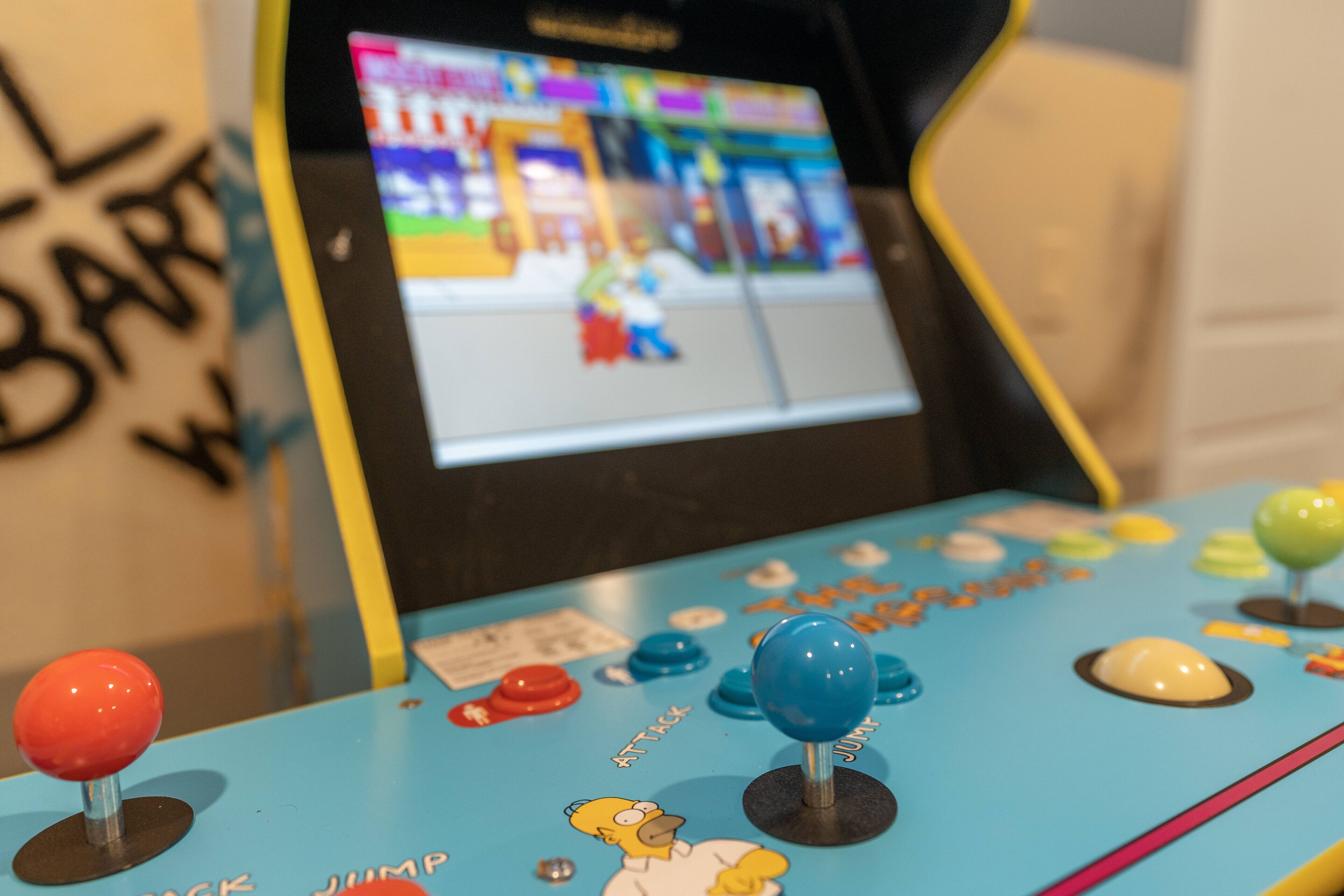 Une salle d’arcade proposant des jeux vidéo, avec des manettes colorées et un écran affichant un jeu.