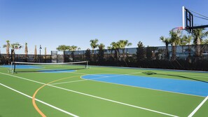 An outdoor tennis court with a net, surrounded by palm trees and a fence. - Last Minute Disney Getaway! Villa with Private Pool & Hot Tub. Book Now! #100817 (Orlando)