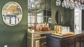 Uma área de bar com espelho, prateleiras com garrafas e balcão.