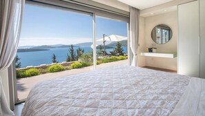 A bedroom with a large bed, a view of the sea, and a balcony with outdoor furniture. - Villa Ino Lefkas - Four Bedroom Villa, Sleeps 8 (Perigiali)