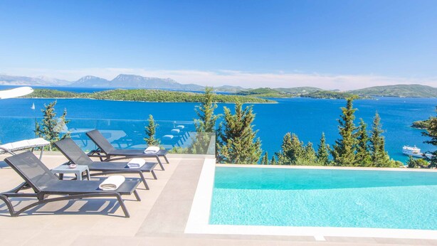 A poolside area with lounge chairs and a view of a large body of water and mountains. - Villa Ino Lefkas - Four Bedroom Villa, Sleeps 8 (Perigiali)