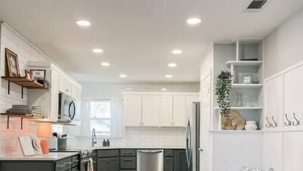 A modern kitchen with white cabinets, a wooden floor, and a built-in dishwasher. - Myrtles on Madison House near ACU (Abilene)