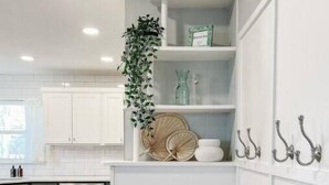A modern kitchen with white cabinetry, a built-in dishwasher, and a wooden floor. - Myrtles on Madison House near ACU (Abilene)