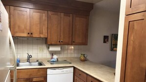Eine Küche mit Holzschränken, einem weißen Geschirrspüler, einer Spüle und einer Arbeitsplatte.
