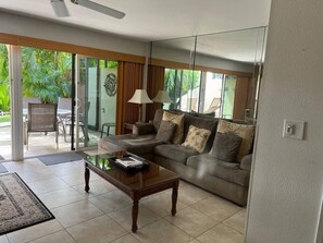 Una sala de estar con sofá, mesa de centro y puerta de cristal que da a un espacio al aire libre.