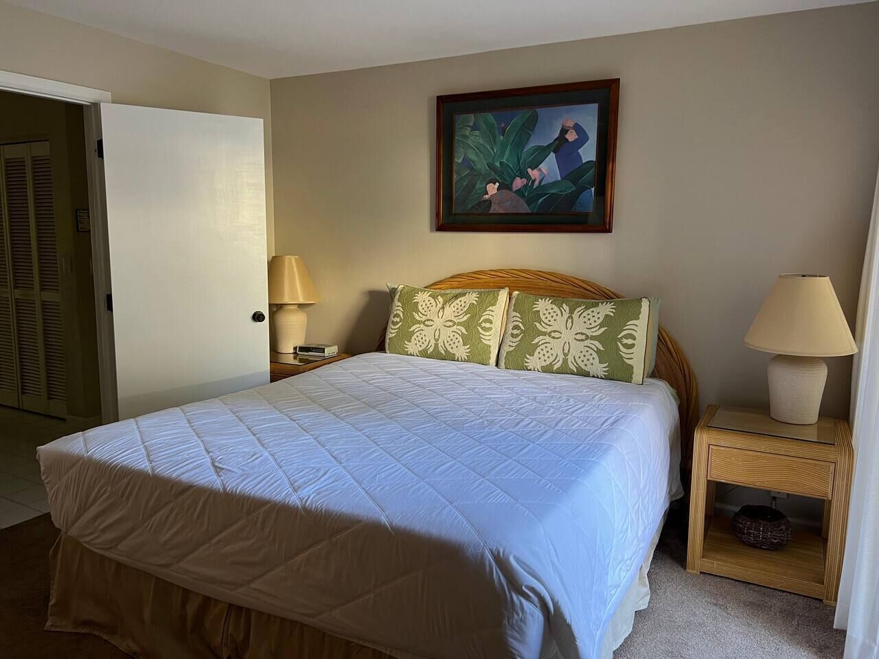 A bedroom with a bed, two bedside tables, a nightstand, a door, and a painting on the wall.
