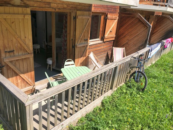 A wooden cabin with a balcony, a table, and chairs.