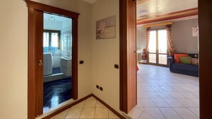 Un pasillo que conduce a una sala de estar con sofá y vistas al exterior.