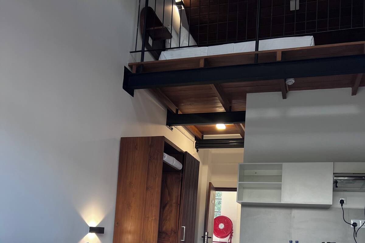 Une chambre comprenant un lit, une armoire en bois, une kitchenette avec un réfrigérateur et un petit coin repas.