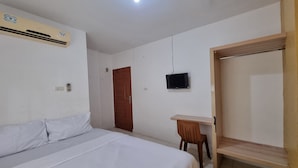 Un dormitorio con cama, escritorio, televisor y armario.