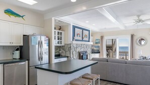 A modern kitchen with a central island, built-in appliances, and a stone backsplash. - Pier Pointe 3B2, Oceanfront Condo, in Emerald Isle, NC! (Emerald Isle)