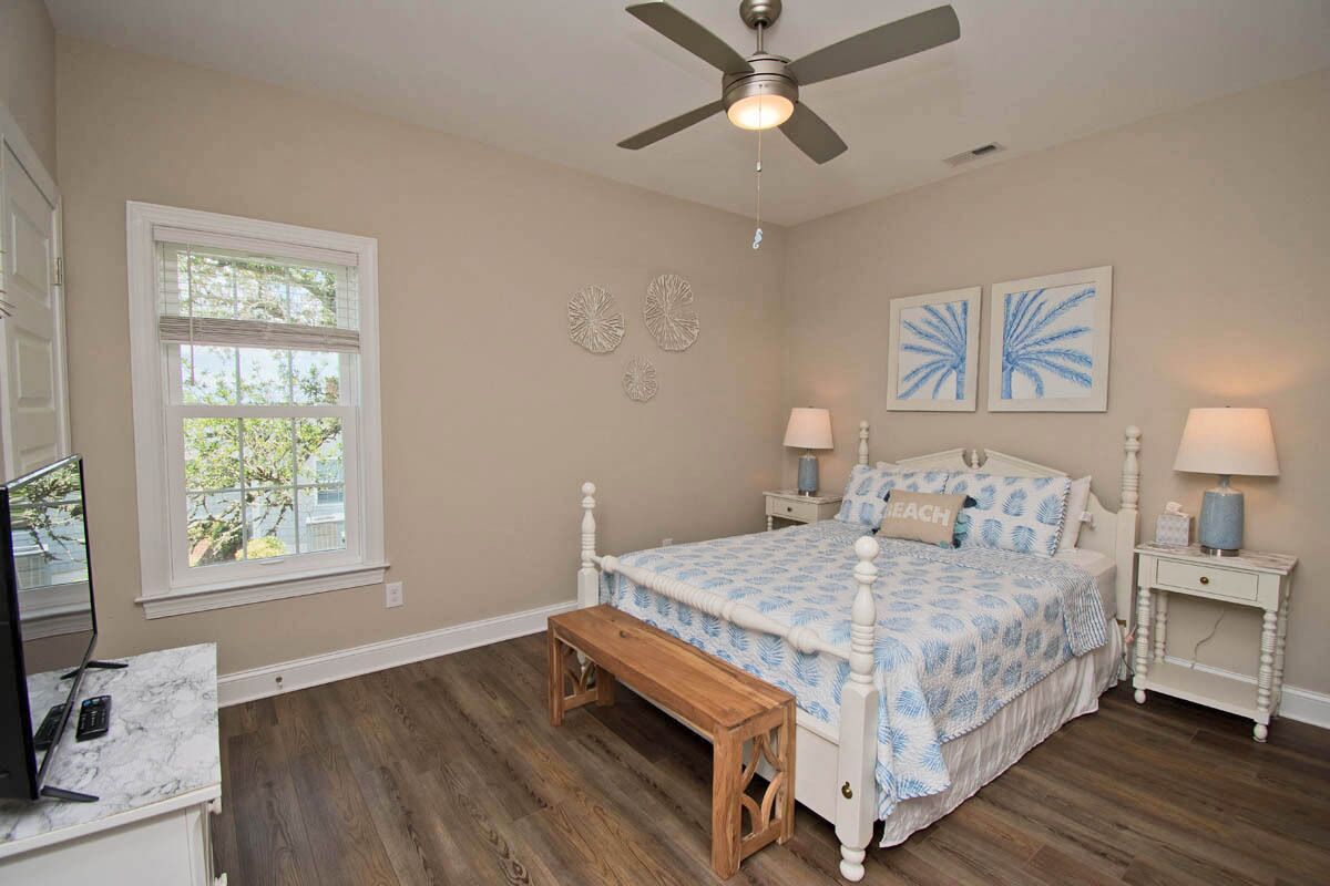 A bedroom with a bed, bedside tables, a ceiling fan, a window, and a wooden bench.