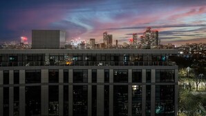 Ein Stadtpanorama im Abenddämmerung mit beleuchteten Gebäuden und einem klaren Himmel.