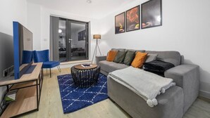 Ein modernes Wohnzimmer mit einem grauen Sofa, blauen Sesseln, einem Couchtisch und einem großen Fenster.