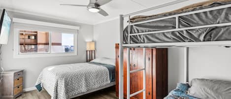 A room with two beds, a ceiling fan, a window, and a wooden wardrobe.