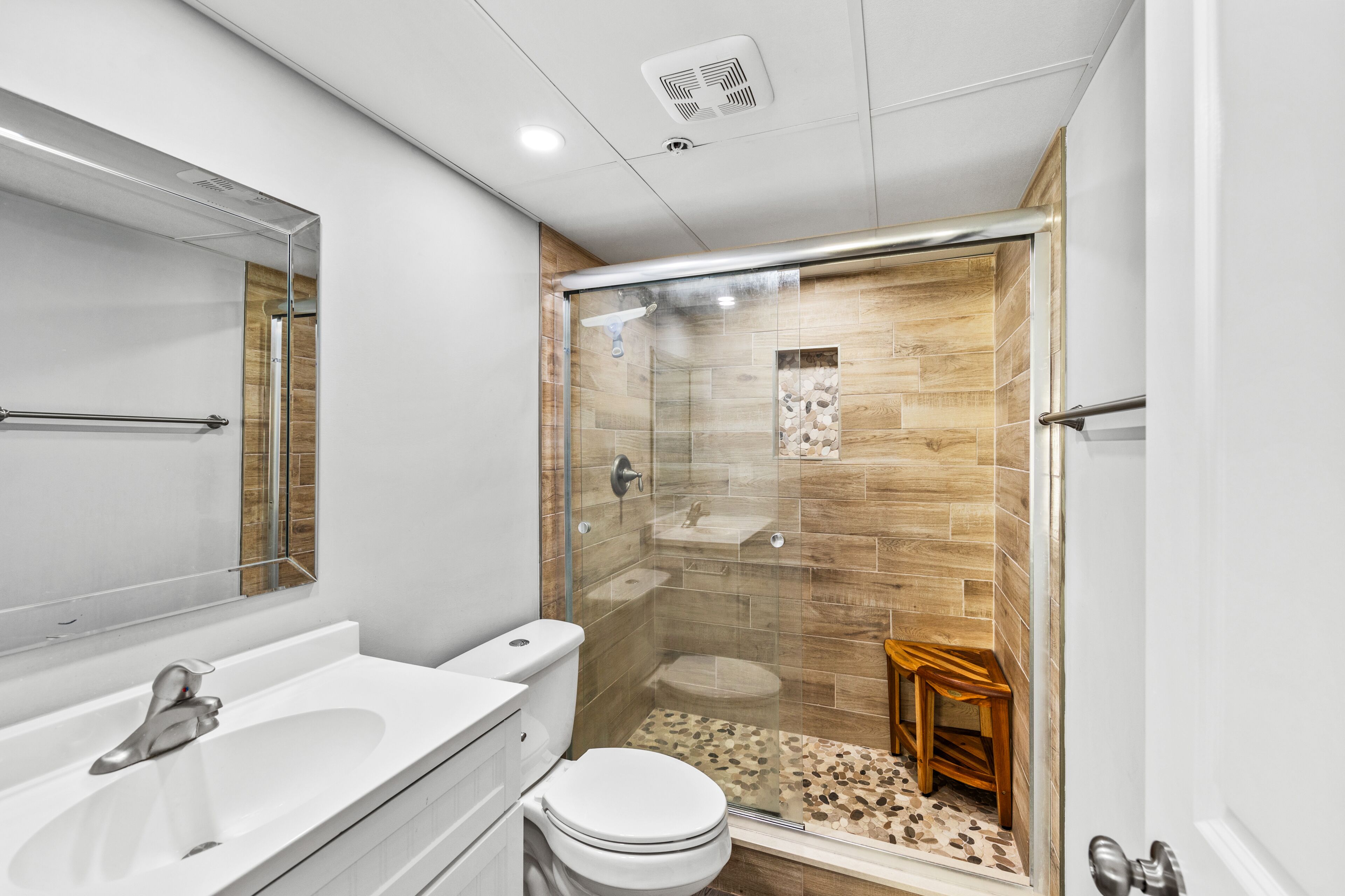 Une salle de bain moderne avec une douche à parois de verre, un lavabo blanc et des toilettes.